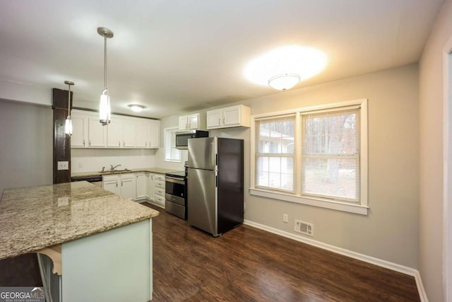 kitchen with light stone countertops, a kitchen breakfast bar, stainless steel appliances, decorative light fixtures, and white cabinetry