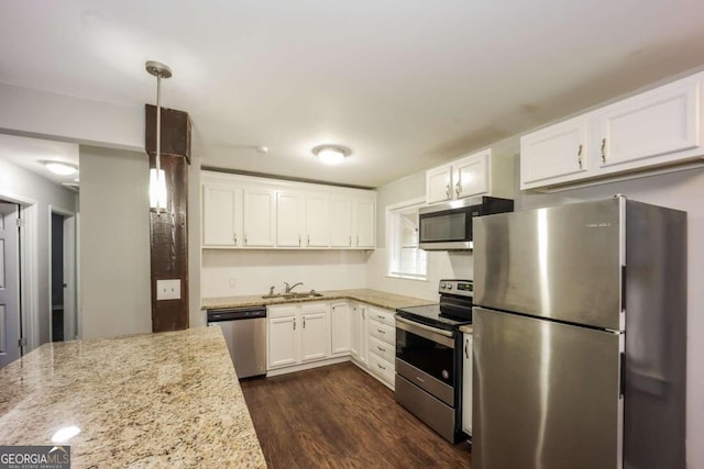 kitchen featuring pendant lighting, dark wood-type flooring, white cabinets, light stone counters, and stainless steel appliances