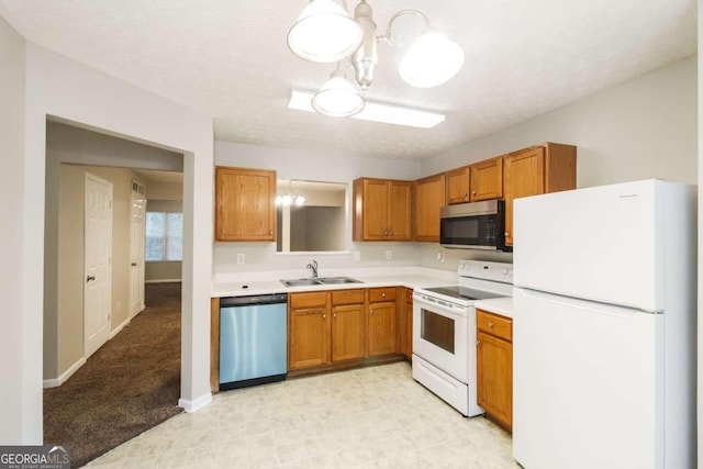 kitchen with sink, an inviting chandelier, a textured ceiling, and appliances with stainless steel finishes