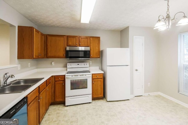 kitchen with pendant lighting, white appliances, sink, a textured ceiling, and a chandelier