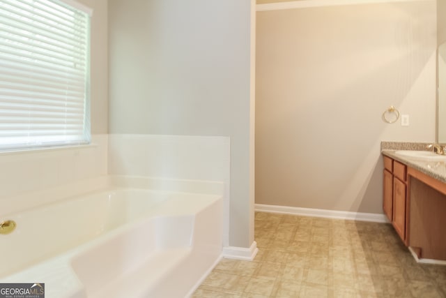 bathroom with a bathtub, vanity, and a healthy amount of sunlight