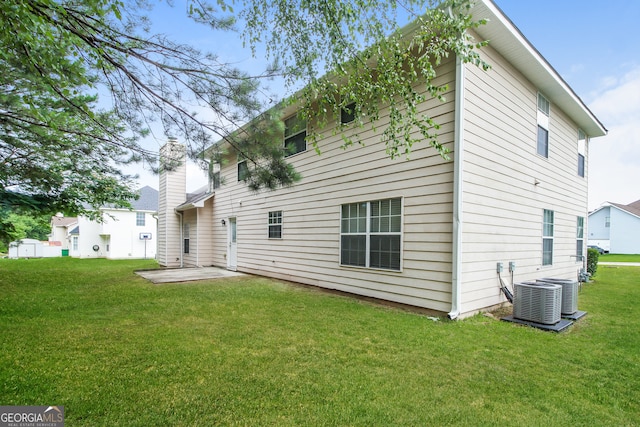 back of property with central AC unit, a patio area, and a lawn