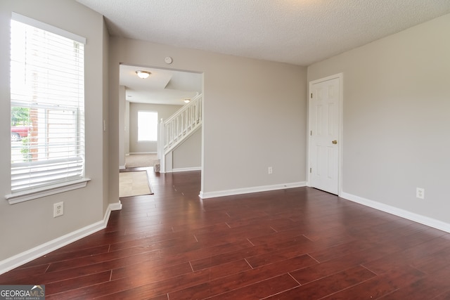 unfurnished room with dark hardwood / wood-style floors and a textured ceiling