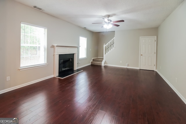 unfurnished living room featuring dark hardwood / wood-style floors, ceiling fan, and a textured ceiling