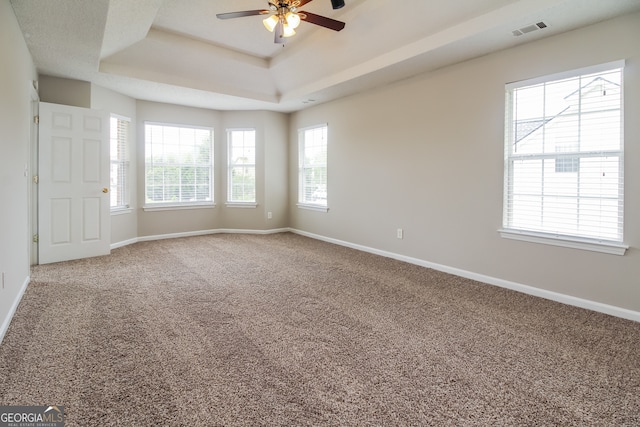 spare room featuring carpet, ceiling fan, and a raised ceiling