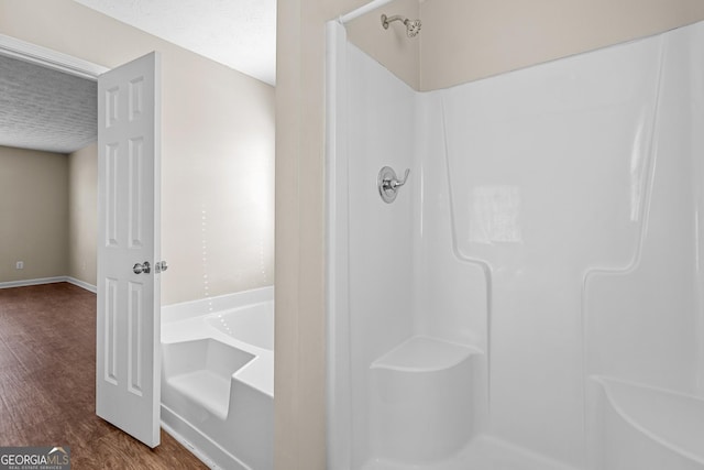 bathroom with hardwood / wood-style floors, a textured ceiling, and separate shower and tub