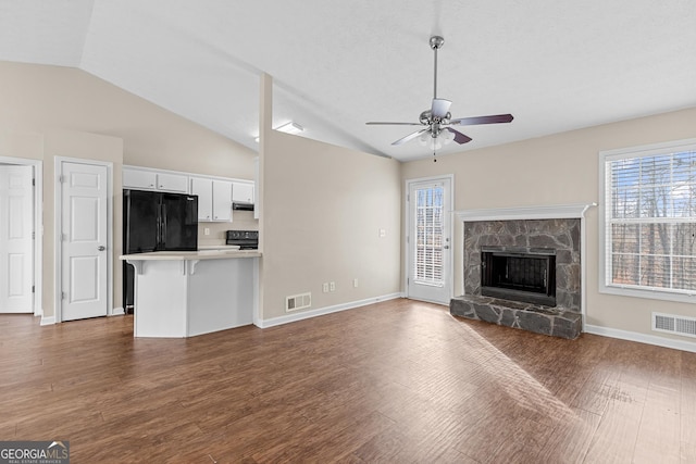 unfurnished living room with vaulted ceiling, dark hardwood / wood-style floors, ceiling fan, and a fireplace