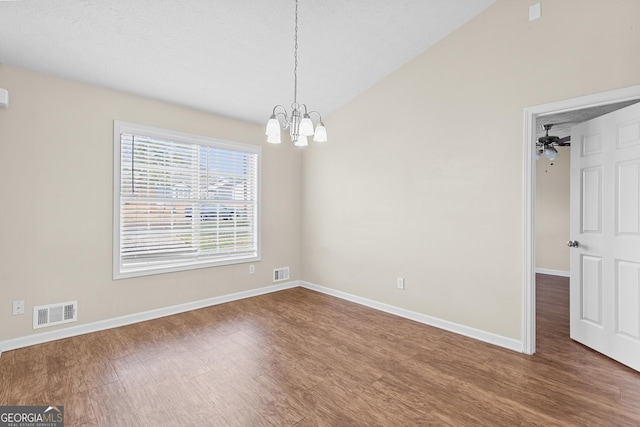 spare room featuring wood-type flooring, vaulted ceiling, and a notable chandelier