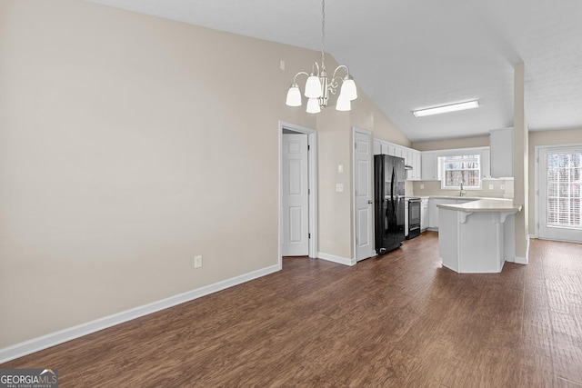 kitchen featuring a breakfast bar area, dark hardwood / wood-style floors, black appliances, white cabinets, and decorative light fixtures