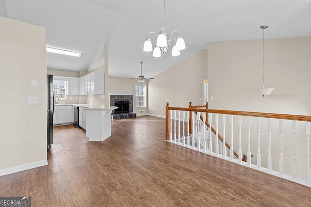 kitchen with pendant lighting, lofted ceiling, dark hardwood / wood-style floors, white cabinets, and stainless steel dishwasher