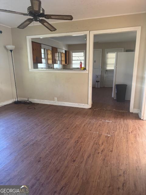 unfurnished living room featuring ceiling fan, plenty of natural light, and dark wood-type flooring