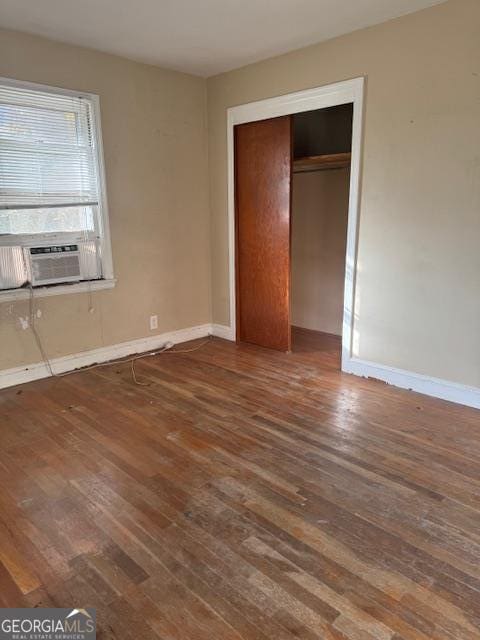 unfurnished bedroom featuring a closet, cooling unit, and dark wood-type flooring