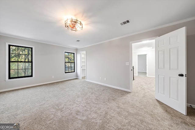 empty room featuring light colored carpet and crown molding