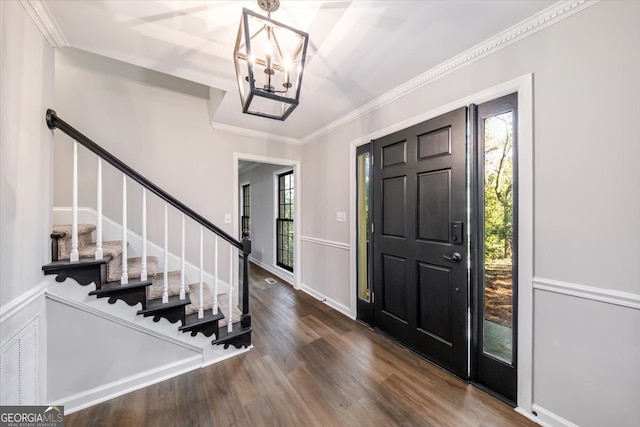 foyer entrance featuring hardwood / wood-style floors, ornamental molding, and an inviting chandelier