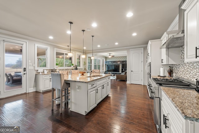 kitchen with hanging light fixtures, a large island, light stone counters, white cabinetry, and stainless steel range