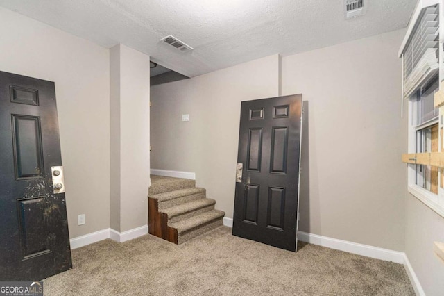 foyer entrance featuring light colored carpet and a textured ceiling