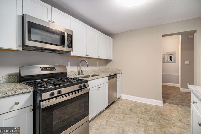 kitchen with light stone counters, a textured ceiling, stainless steel appliances, sink, and white cabinets