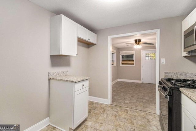 kitchen featuring white cabinets, ceiling fan, a textured ceiling, appliances with stainless steel finishes, and light stone counters