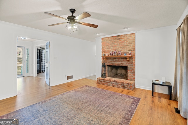 living room featuring a textured ceiling, light hardwood / wood-style floors, a brick fireplace, and ornamental molding