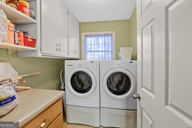 laundry room featuring washing machine and clothes dryer, cabinets, and a textured ceiling