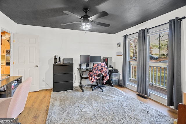 office with ceiling fan, light wood-type flooring, and a textured ceiling