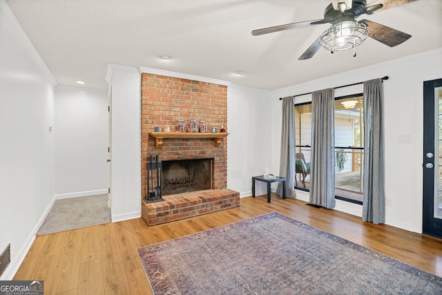 unfurnished living room featuring crown molding, a fireplace, ceiling fan, and wood-type flooring