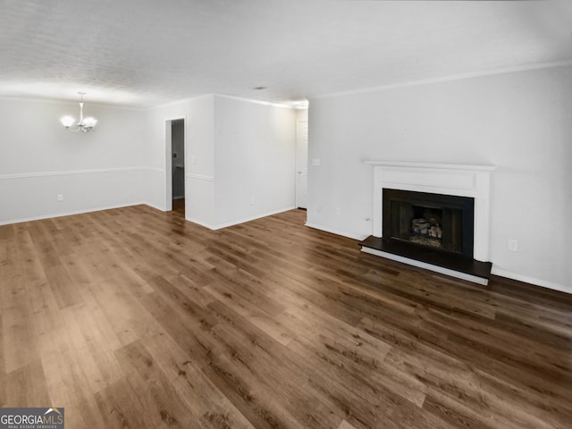 unfurnished living room featuring dark hardwood / wood-style flooring, an inviting chandelier, and crown molding