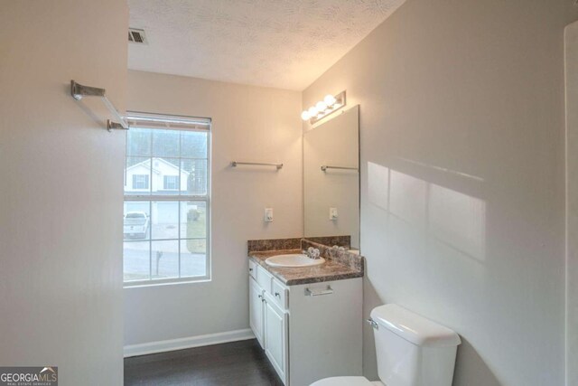 bathroom with hardwood / wood-style floors, vanity, a textured ceiling, and toilet