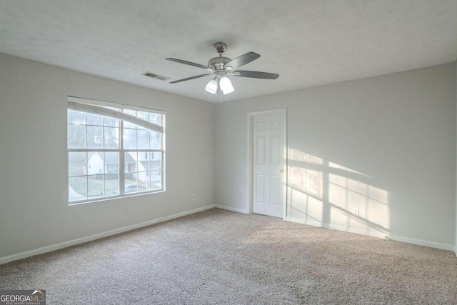 empty room with ceiling fan, carpet floors, and a textured ceiling