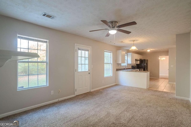 unfurnished living room featuring ceiling fan, light colored carpet, and a textured ceiling