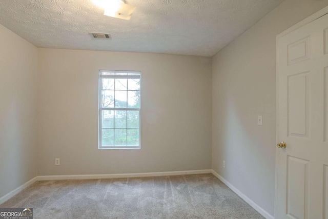 empty room featuring a textured ceiling and light colored carpet