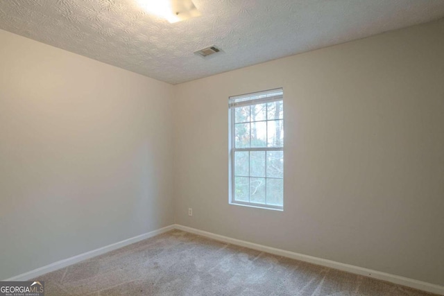 empty room with a textured ceiling and light colored carpet