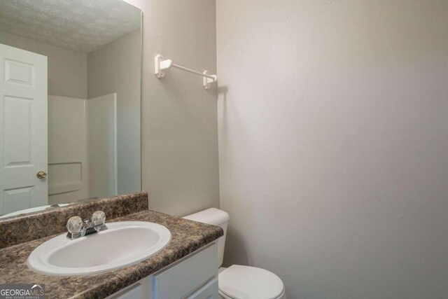 bathroom featuring vanity, a textured ceiling, and toilet