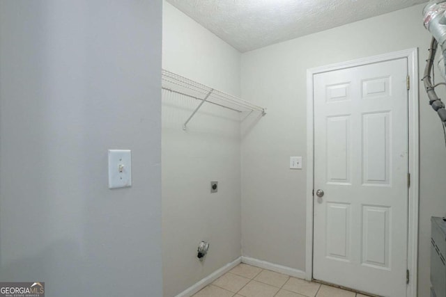 laundry area with a textured ceiling, electric dryer hookup, and light tile patterned flooring