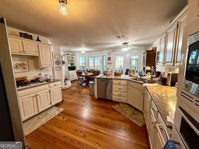 kitchen featuring sink, a textured ceiling, tasteful backsplash, wood-type flooring, and stainless steel appliances