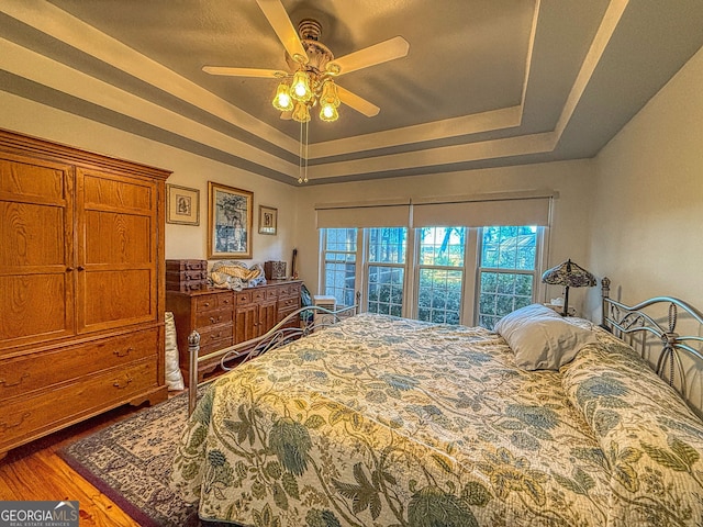 bedroom with a tray ceiling, ceiling fan, and hardwood / wood-style floors