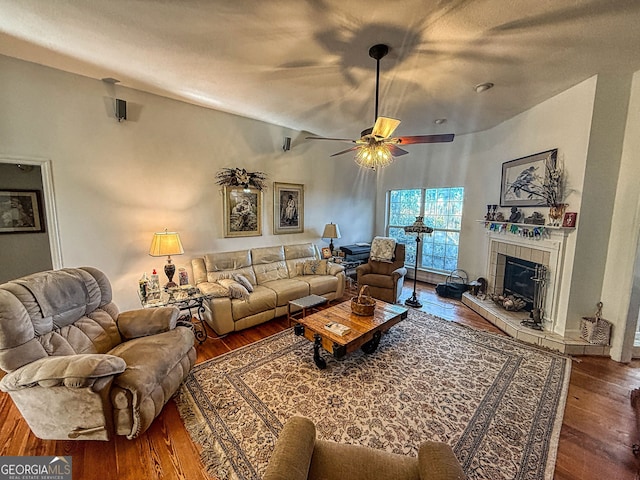 living room featuring a fireplace, ceiling fan, and dark wood-type flooring