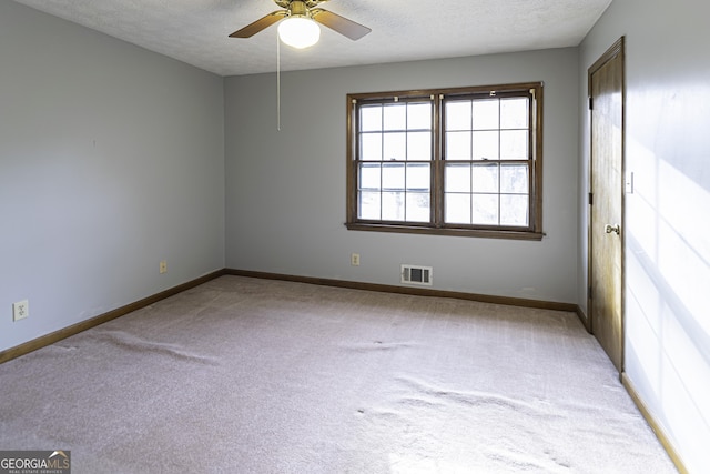 empty room with ceiling fan, light colored carpet, and a textured ceiling