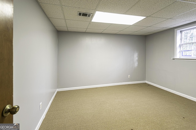 empty room featuring a paneled ceiling and carpet