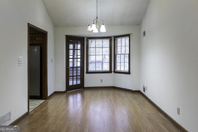 interior space featuring light hardwood / wood-style floors, an inviting chandelier, and lofted ceiling