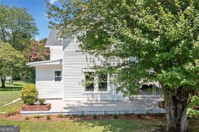 view of side of property with a lawn and a patio area