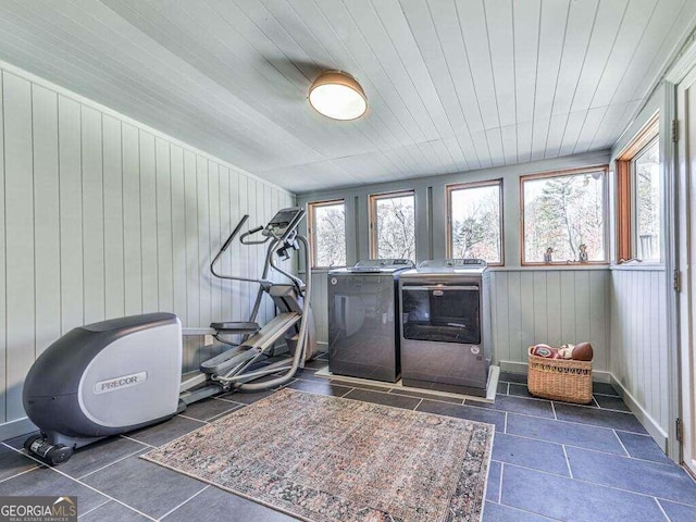 workout area with dark tile patterned floors, wood walls, separate washer and dryer, and wooden ceiling