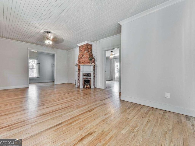 unfurnished living room featuring ceiling fan, wooden ceiling, a stone fireplace, light wood-type flooring, and ornamental molding