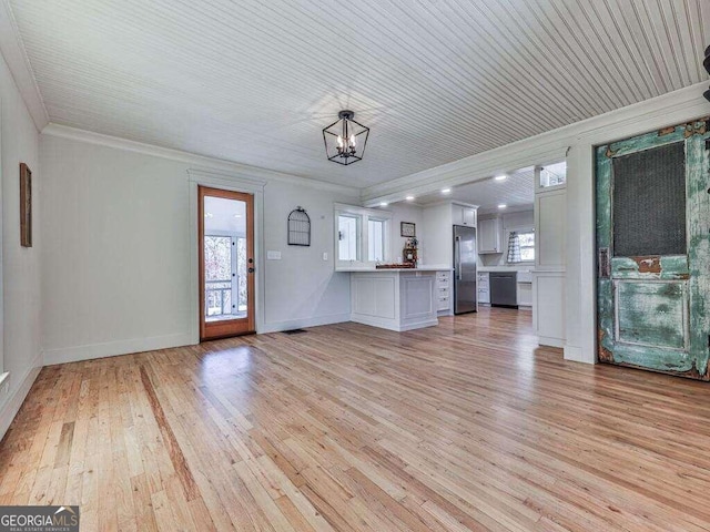 unfurnished living room with light wood-type flooring, an inviting chandelier, and crown molding