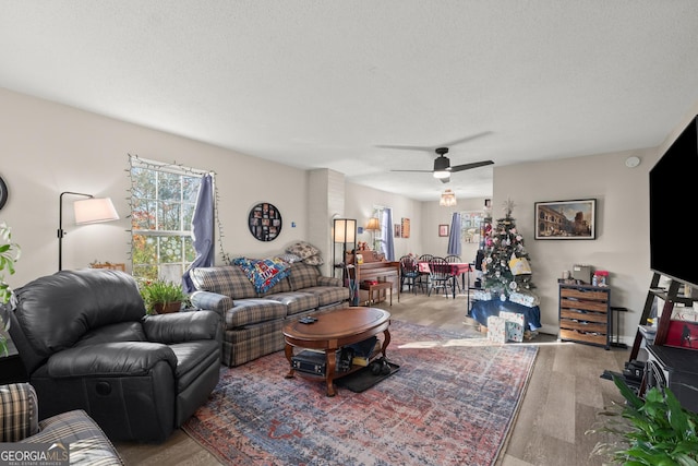 living room featuring hardwood / wood-style flooring, a textured ceiling, and ceiling fan