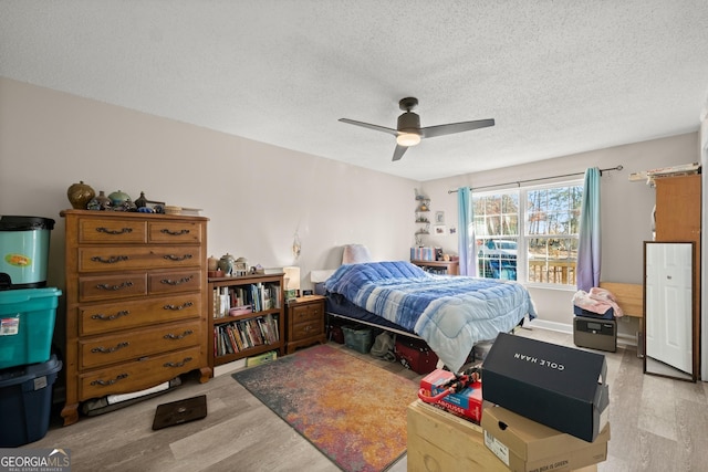 bedroom featuring ceiling fan, a textured ceiling, and light hardwood / wood-style floors