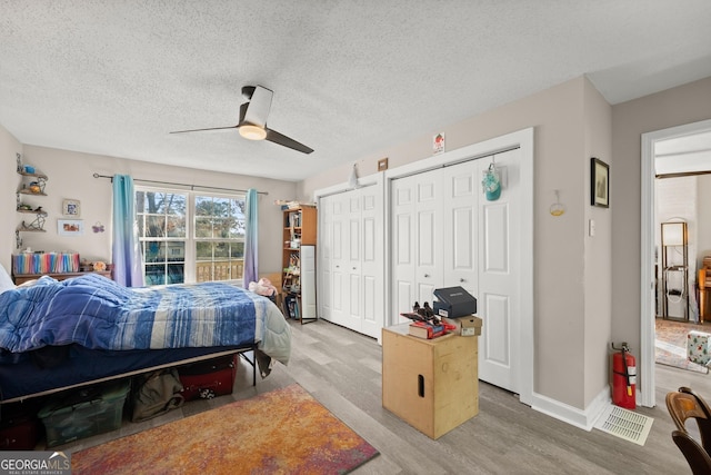 bedroom featuring hardwood / wood-style flooring, a textured ceiling, and two closets