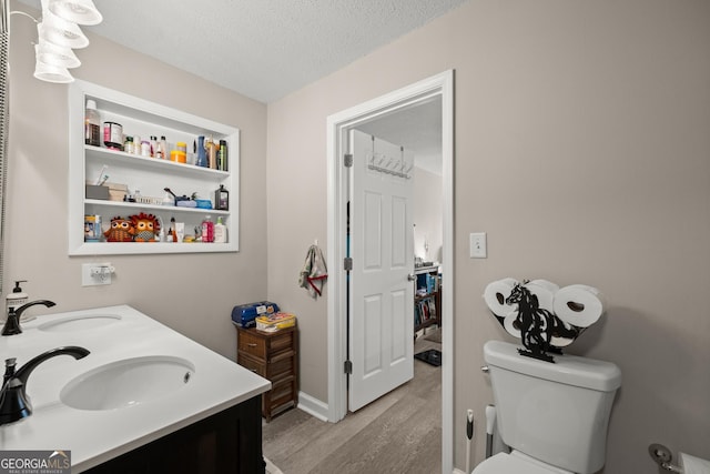 bathroom featuring vanity, hardwood / wood-style floors, a textured ceiling, and toilet