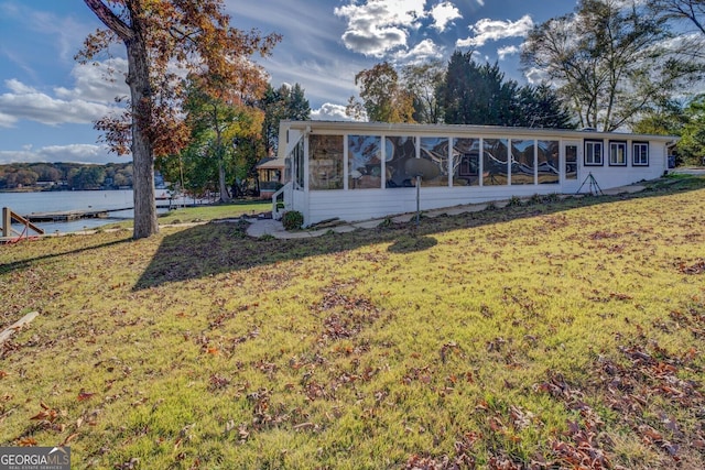 back of house with a yard, a sunroom, and a water view