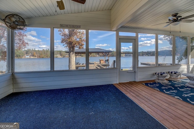 unfurnished sunroom featuring lofted ceiling, wooden ceiling, ceiling fan, and a water view